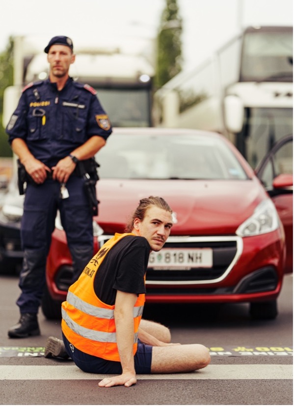 Das Bild zeigt Aktivist Valentin Bast bei einer Klebeaktion. Die Polizei ist involviert.